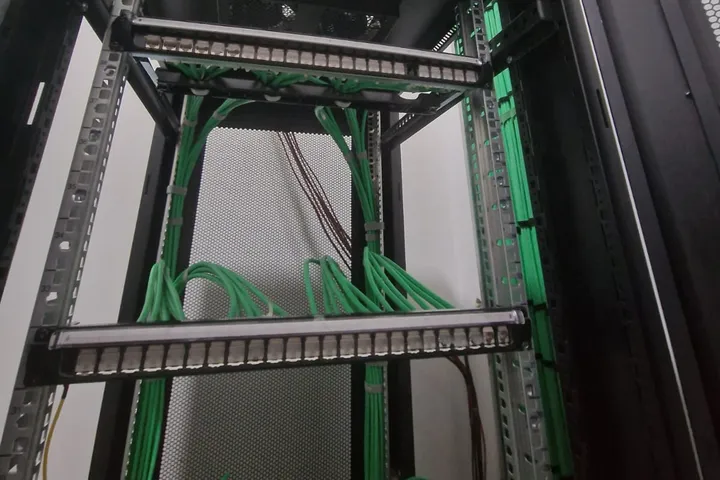 Rack de comunicaciones con cableado verde ordenado y peinado en el patch panel