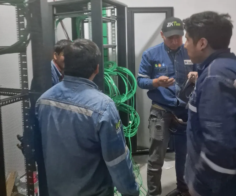Equipo de H&S coordinando el trabajo frente a un rack de comunicaciones con cableado verde